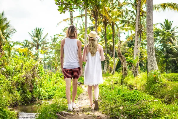 Una joven pareja de luna de miel caminando entre arrozales. Hermoso viaje de recién casados a la isla de Bali, Indonesia. Naturaleza, verano, verde, brillante . — Foto de Stock