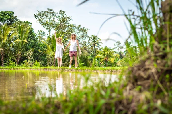 Una joven pareja de luna de miel caminando entre arrozales. Hermoso viaje de recién casados a la isla de Bali, Indonesia. Naturaleza, verano, verde, brillante . — Foto de Stock