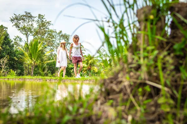 Young honeymoon couple walking among rice fields. Beautiful trip of newleds to Bali island, Indonesia. Nature, summer, green, bright.