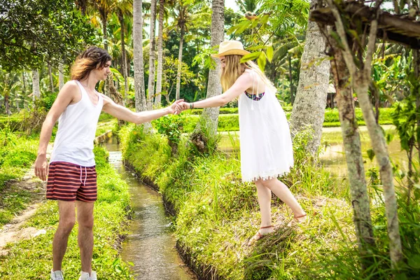 Una joven pareja de luna de miel caminando entre arrozales. Hermoso viaje de recién casados a la isla de Bali, Indonesia. Naturaleza, verano, verde, brillante . — Foto de Stock