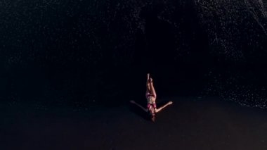 4 k hava üst siyah volkanik kum ile sahilde bikinili genç kadının uçan video görüntüleyin. Bali Adası.