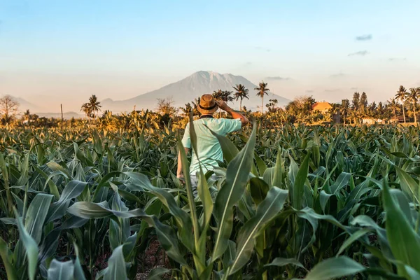 Joven turista viajero en un sombrero de paja sobre un fondo de volcán al atardecer. La isla de Bali. Países Bajos . — Foto de Stock