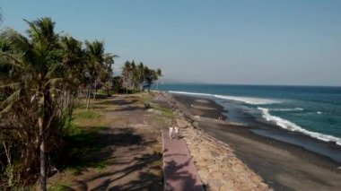 4k hava genç çift vahşi siyah kum Plajı üzerinde uçan görüntülerini robot. Bali Adası.