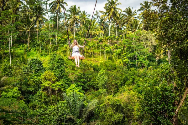 Joven turista balanceándose sobre el acantilado en la selva tropical de una isla tropical de Bali . — Foto de Stock