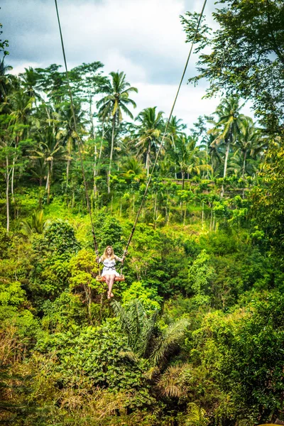 Joven turista balanceándose sobre el acantilado en la selva tropical de una isla tropical de Bali . — Foto de Stock