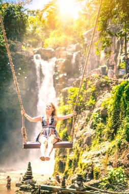 Bali, Endonezya - 24 Ağustos 2018: Bali orman şelale arka plan üzerinde sallanan genç kadın.