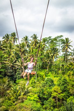 Tropikal bir Bali Adası'nın orman yağmur ormanlarında uçurumdaki sallanan uzun saçlı Genç turist adam.