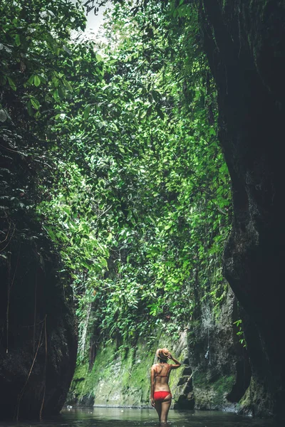 Fiatal nő turista keresi a vízesés a dzsungel. Ökoturizmus koncepció kép utazási lány. Bali szigetén. — Stock Fotó