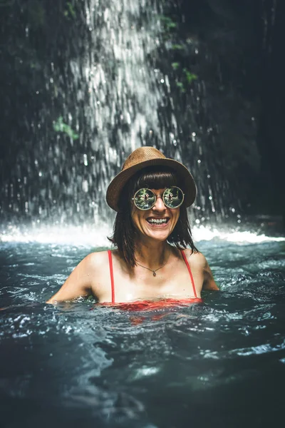 Jonge vrouw toeristische glimlachend in de diepe jungle met waterval. Echte avontuur concept. Bali eiland. — Stockfoto