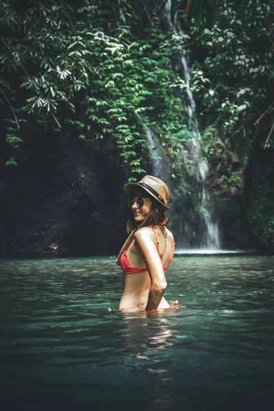Jonge vrouw toeristische met stro hoed in de diepe jungle met waterval. Echte avontuur concept. Bali eiland. — Stockfoto
