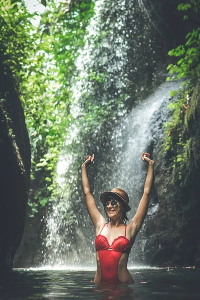 Jonge vrouw voor toeristen in de diepe jungle met waterval. Echte avontuur concept. Bali eiland. — Stockfoto