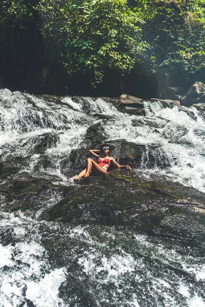 Art arda sıralı şelale Bali Adası üzerinde kırmızı mayo genç kadın.