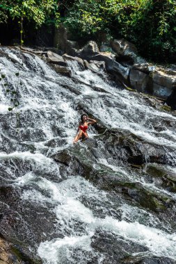 Genç kadın basamaklı şelale Bali Adası üzerinde kırmızı mayo. Endonezya.