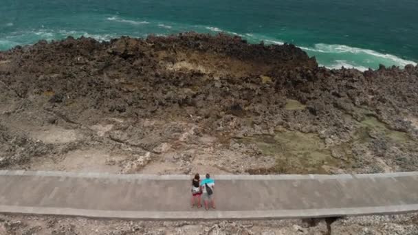 4k antenn flyger drönaren video av ungt par turister på den vilda klippiga stranden. Ön Bali. — Stockvideo