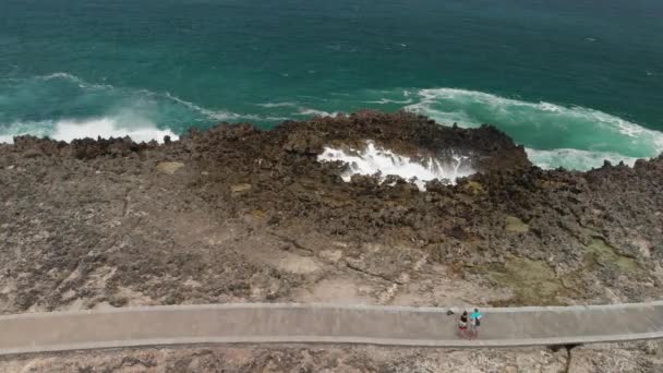 4k luchtfoto vliegende drone video van het jonge paar toeristen op de wilde, rotsachtige strand. Bali eiland. — Stockvideo
