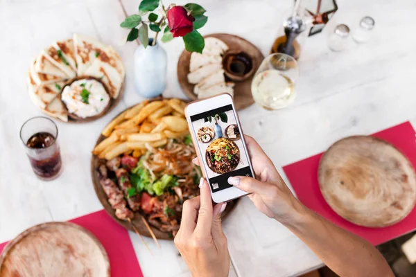 Kadın alarak fotoğraf karışımı ızgara yemek restoranda smartphone kullanarak. Bali Adası.
