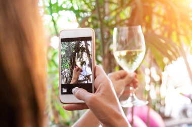Kadın alarak fotoğraf onun smartphone restoranda beyaz şarap.
