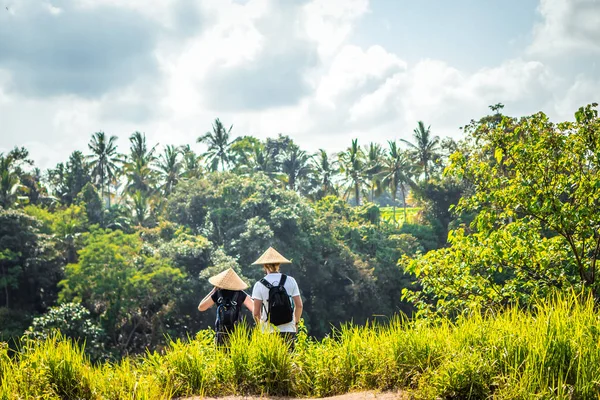 Un par de turistas con sombreros en el fondo de la selva tropical al aire libre. Isla de Bali . — Foto de Stock