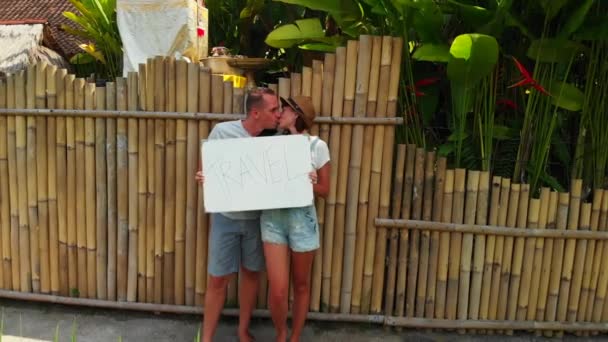 Pareja joven sosteniendo pizarra con viaje de texto. Concepto de viaje, imágenes de aviones no tripulados voladores. Fondo verde. Isla de Bali . — Vídeo de stock