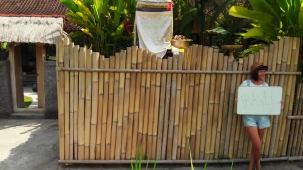 Giovane donna in possesso di lavagna bianca con viaggi di testo. Concetto di viaggio, riprese di droni volanti. Sfondo verde. Isola di Bali . — Video Stock
