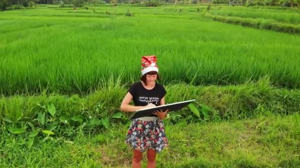 Feliz Ano Novo 2019. 4K voando drone vídeo de jovem mulher com chapéu de santa e quadro branco com texto escrito à mão posando entre campo de arroz verde na ilha de Bali . — Vídeo de Stock