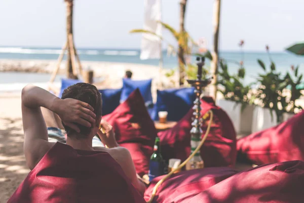 Adam sigara nargile bir sahil tarafı restoranı deniz yanında tarih. Shisha yasaktır. Bali Adası.