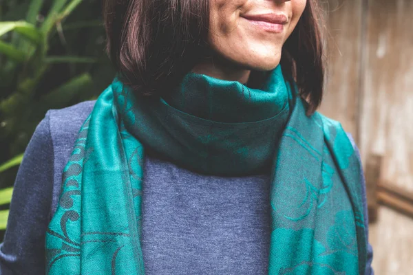 Woman wearing warm cashmere scarf on a tropical background.