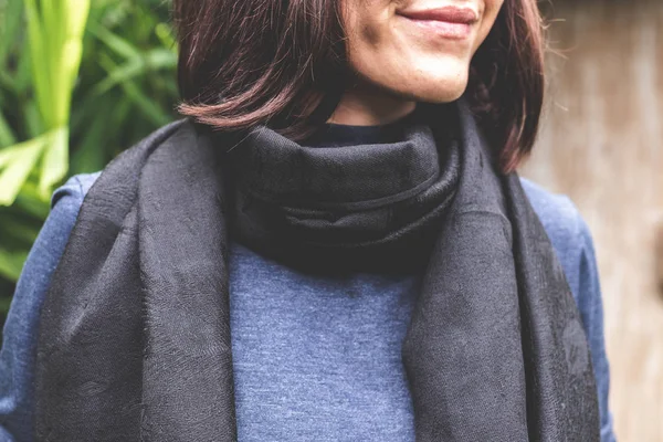 Woman wearing warm cashmere scarf on a tropical background.