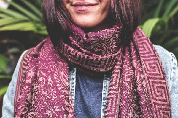 Woman wearing warm cashmere scarf on a tropical background.