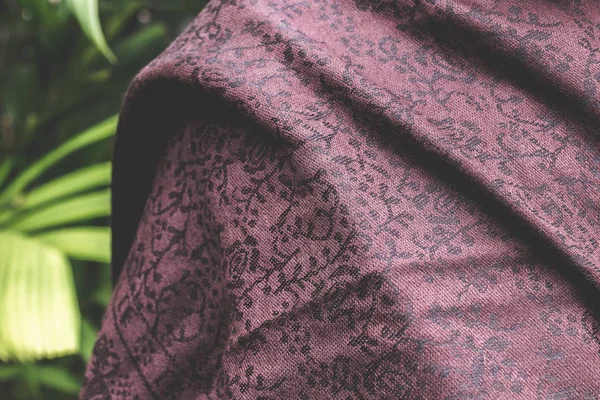 Woman wearing warm cashmere scarf on a tropical background.