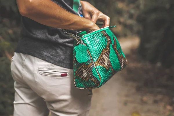 Woman with luxury snakeskin python handbag in the tropical forest. Bali island.