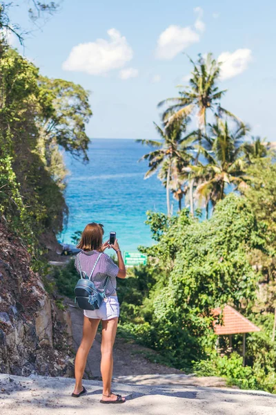 Genç kadın turist alarak fotoğraf güzel tropikal peyzaj onun smartphone. Bali Adası.