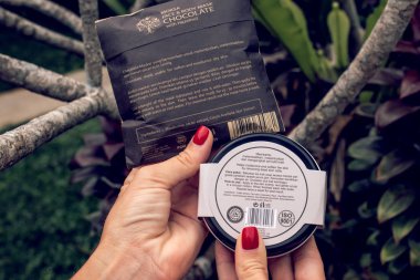 Bali, Endonezya - 13 Aralık 2018: Bali dili doğal kozmetik yeşil tropikal arka plan üzerinde kadın el.