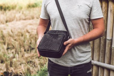 Lüks yılan derisi python deri çanta olan bir adam. Bali Adası arka plan.