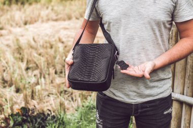 Lüks yılan derisi python deri çanta olan bir adam. Bali Adası arka plan.