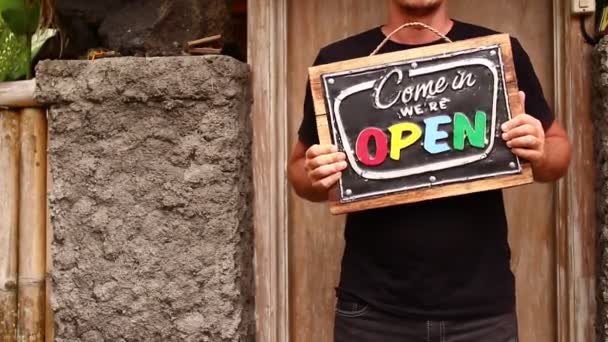 Cartel abierto en las manos de un hombre sobre un fondo de naturaleza tropical. Tiro en la isla de Bali, full HD . — Vídeos de Stock