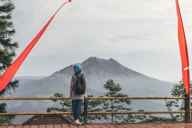 Genç kadın bir volkan Batur arka plan, Bali Adası üzerinde motosiklet kask içinde.