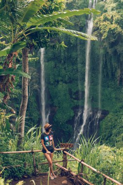 Genç kadın bir harika Sekumpul şelale Bali Adası, Endonezya'nın derin yağmur ormanları içinde poz. Asya.