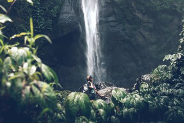 Young woman posing on a great Sekumpul waterfall in the deep rainforest of Bali island, Indonesia.