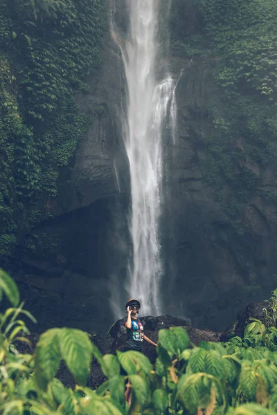 Young woman posing on a great Sekumpul waterfall in the deep rainforest of Bali island, Indonesia.