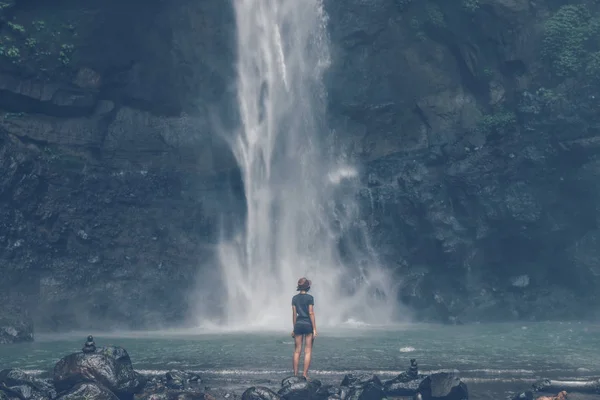 Young woman posing on a great Sekumpul waterfall in the deep rainforest of Bali island, Indonesia. — Stock Photo, Image