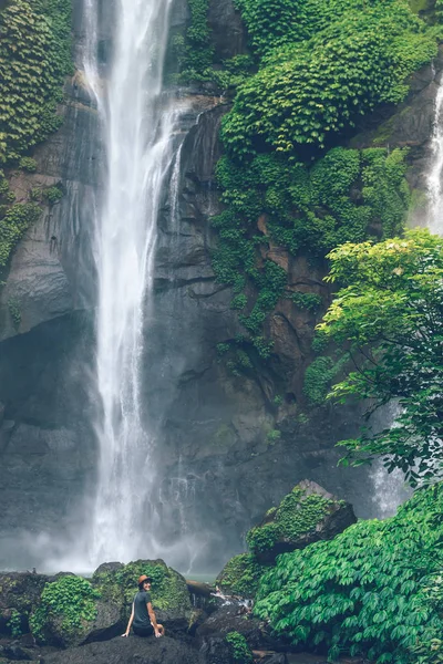 Young woman posing on a great Sekumpul waterfall in the deep rainforest of Bali island, Indonesia. — стокове фото