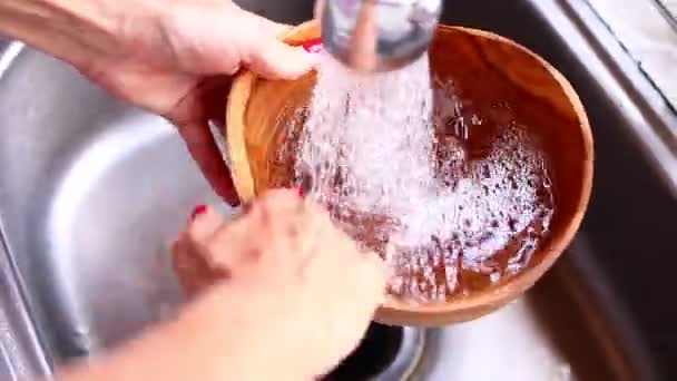 Женские руки моют деревянную чашку из тика в помещении . — стоковое видео