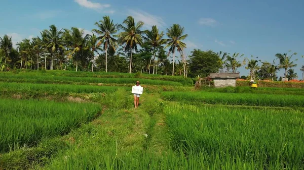 Молодая женщина на улице с белой доской и надписью "тропический". Запись беспилотника. Зеленый яркий фон. Концепция путешествий. Бали . — стоковое фото