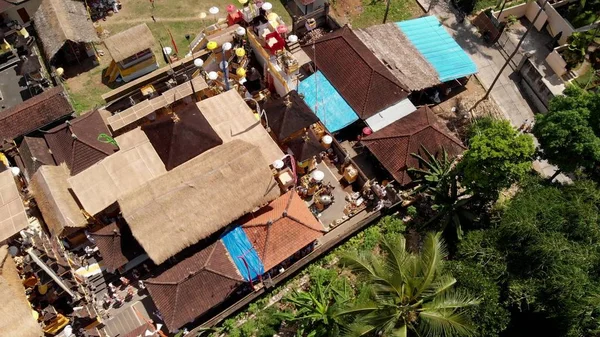 Vídeo de vuelo aéreo de 4K de casas balinesas durante la gran celebración. Ceremonia de Bali en el pueblo, Ubud. Techos de casas balinesas . —  Fotos de Stock