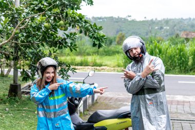 Bali, Endonezya - 3 Ocak 2019: Yağmurluklar scooter üzerinde eğleniyor bir doğa arka plan genç çift.