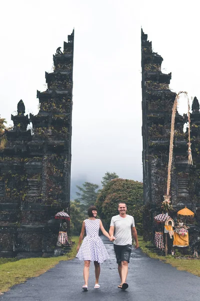 Young honeymoon couple on a big balinese gates background. Bali island, Indonesia.