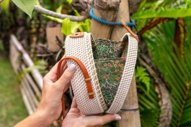 Stylich Eko dostu rattan çanta tropikal bir arka plan üzerinde kadın elle. Bali Adası.