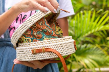 Stylich Eko dostu rattan çanta tropikal bir arka plan üzerinde kadın elle. Bali Adası.