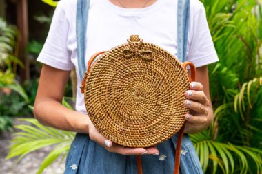 Stylich Eko dostu rattan çanta tropikal bir arka plan üzerinde kadın elle. Bali Adası.